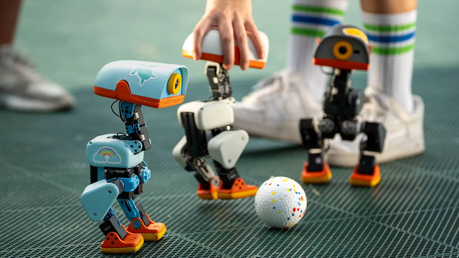 Three Microduck robots gathered around a ball on a play surface