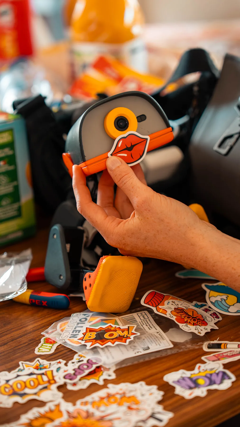 Hands holding a Microduck robot while applying a decorative sticker